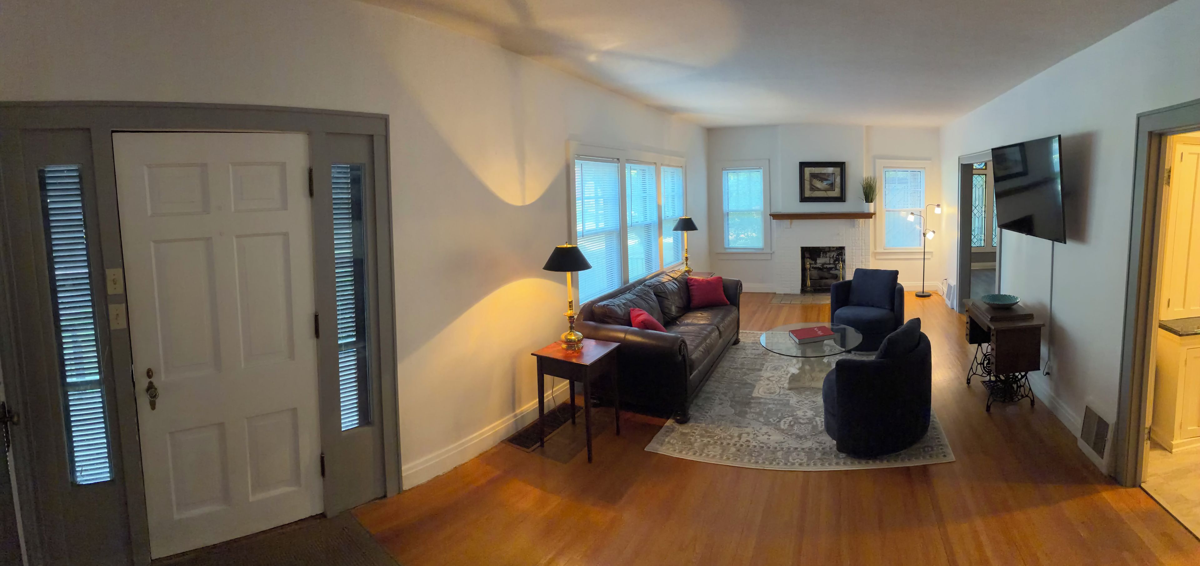 A spacious living room with a fireplace, a sofa, a coffee table, and a TV mounted on the wall.