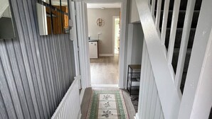A hallway with a patterned rug, a staircase with white railings, and a mirrored wall. - Serene 3-bedroom City Home in charming Kilkenny perfect for relaxing stays (Kilkenny)