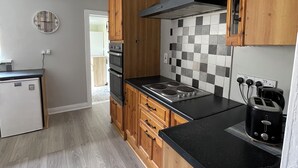 A kitchen with wooden cabinets, a black countertop, a tiled backsplash, and a built-in oven. - Serene 3-bedroom City Home in charming Kilkenny perfect for relaxing stays (Kilkenny)