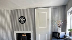 A kitchen with a built-in microwave, a sink, a wooden dining table with chairs, a decorative sign, and a fireplace. - Serene 3-bedroom City Home in charming Kilkenny perfect for relaxing stays (Kilkenny)