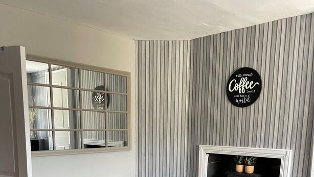 A dining area with a wooden table, two chairs, a mirror, a fireplace, and a wall with a striped pattern. - Serene 3-bedroom City Home in charming Kilkenny perfect for relaxing stays (Kilkenny)