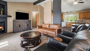 Ein Wohnzimmer mit Kamin, Ledersofas, einem Couchtisch und einem Fernseher.