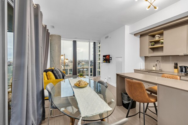 Un apartamento moderno con comedor, cocina y amplios ventanales con vistas a la ciudad.