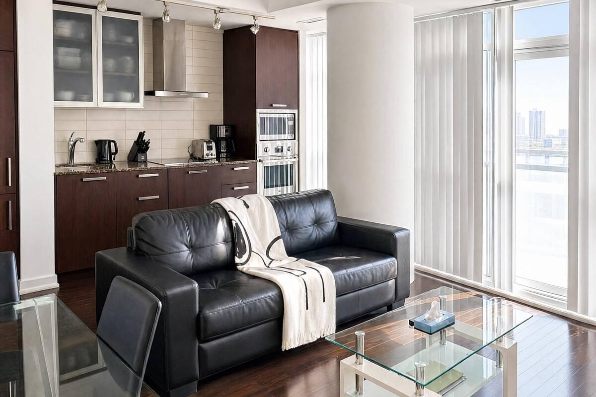 Una sala de estar moderna con una mesa de centro de vidrio, un sofá de cuero y un comedor con una mesa y sillas de vidrio.