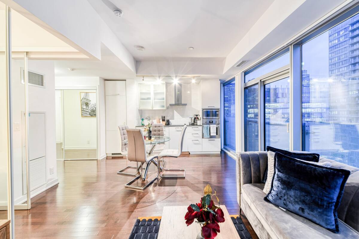 Una cocina moderna con armarios blancos, electrodomésticos de acero inoxidable y un amplio ventanal con vistas a la ciudad.