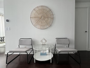Una habitación moderna con dos sillas grises, una mesita redonda y una gran obra de arte circular en la pared.