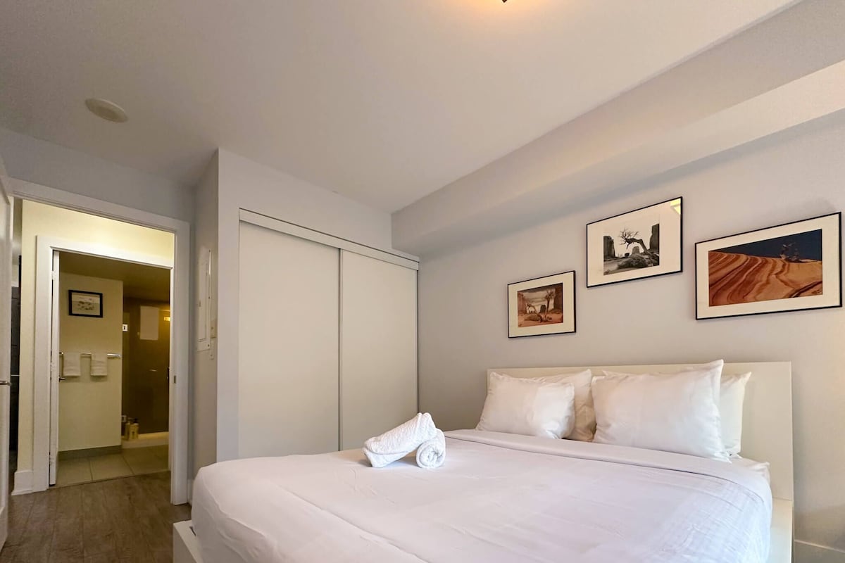 A hotel room with a large bed, a wardrobe, and a bathroom visible through an open door.
