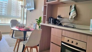 Une cuisine moderne équipée d’un four à micro-ondes, d’un four traditionnel et d’un coin repas avec des chaises et une table.