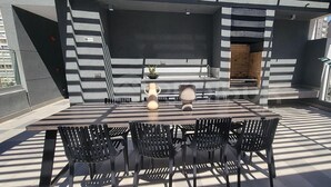 Une terrasse extérieure avec une table et des chaises, une plante en pot et un mur en briques.