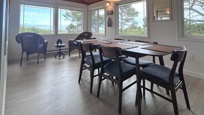 Een eetruimte met een houten plafond, grote ramen en uitzicht op de omgeving.