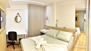 A hotel room with a bed, a desk, a chair, a mirror, a nightstand, and a bedside table. - Vacanze - Monteverdi (Maceió)