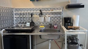 Une petite cuisine équipée comprenant un évier, une cuisinière et des étagères de rangement.