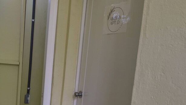 Une porte fermée avec une pancarte indiquant « APPARTEMENT AIRBNB, porte D ».