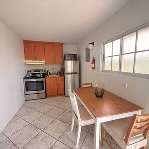 A kitchen with wooden cabinets, a stainless steel stove, a refrigerator, and a dining table with chairs.