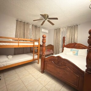 A room with a bunk bed, a single bed, a ceiling fan, and curtains. - Family BBQ getaway, 2 pools, walk to Playa Santa (Guanica)