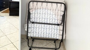 A room with a white closet, a black dresser, and a metal drying rack. - Brisas Apt | Comfort & WiFi with A/C (Yauco)