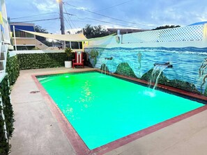 A swimming pool with a mural of sea creatures on the wall, surrounded by a hedge and a white fence. - Private balcony, near Playa Santa (Guanica)