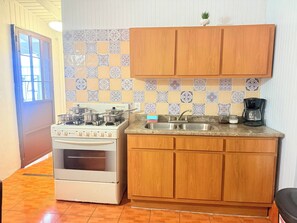 Una cocina con estufa, horno, pileta y armarios de madera.
