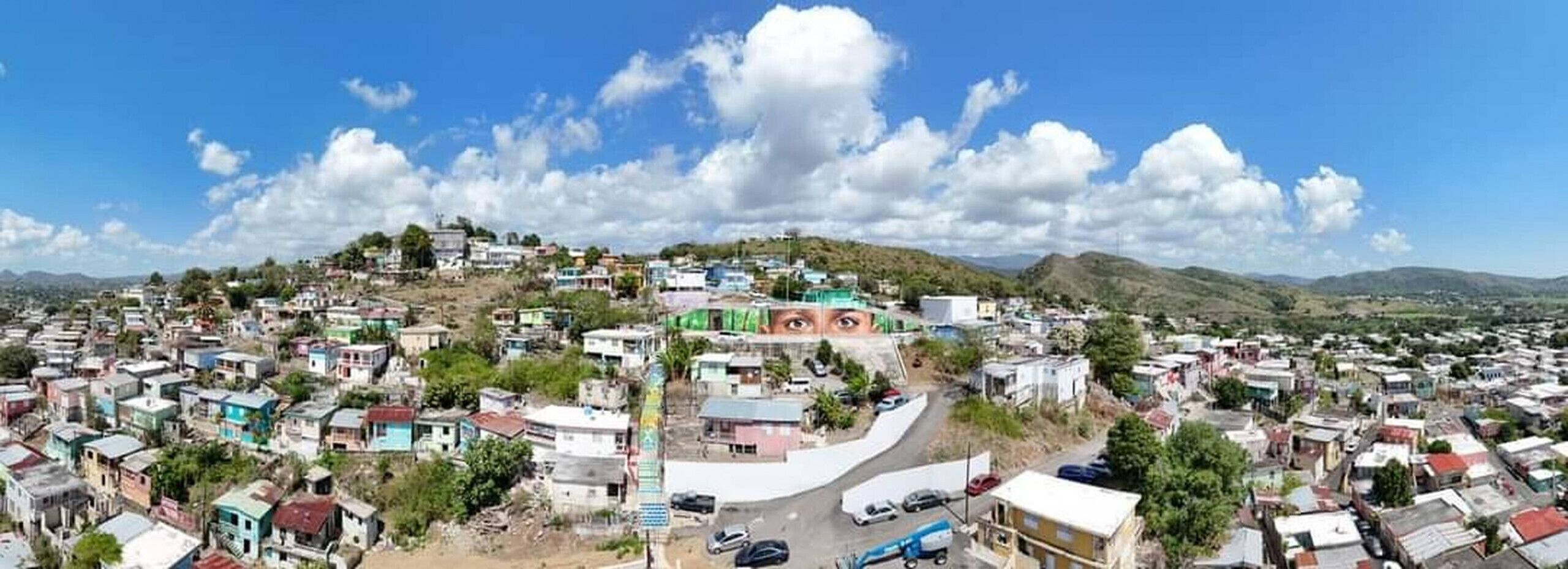 A panoramic view of a densely populated town with a prominent hill in the background.