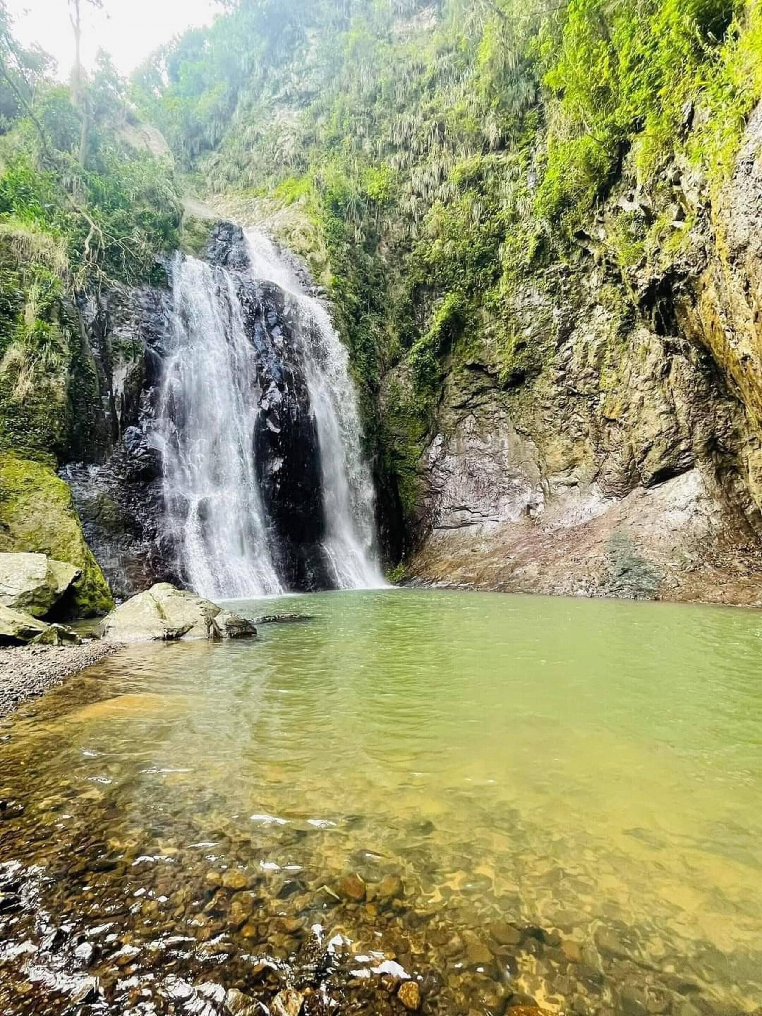 Una cascata con acque limpide, circondata da rocce e vegetazione.