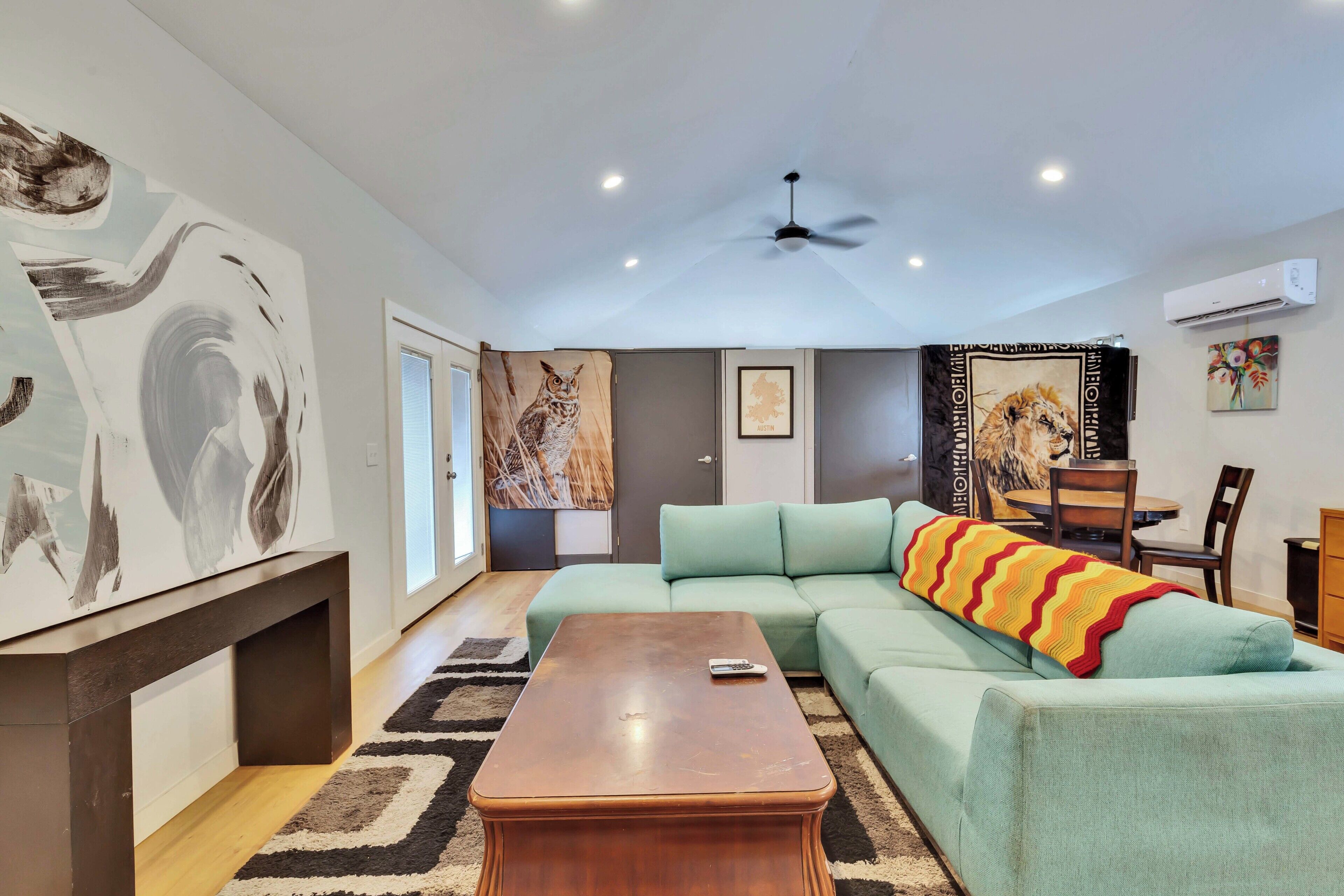 A living room with a sectional sofa, a coffee table, and artwork on the walls.