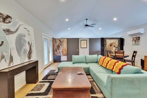 Ein Wohnzimmer mit Ecksofa, Couchtisch und Bildern an den Wänden.