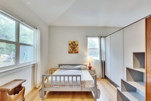 Ein Schlafzimmer mit einem Bett, einem Nachttisch, einer Lampe, einem Fenster und einem Bild an der Wand.