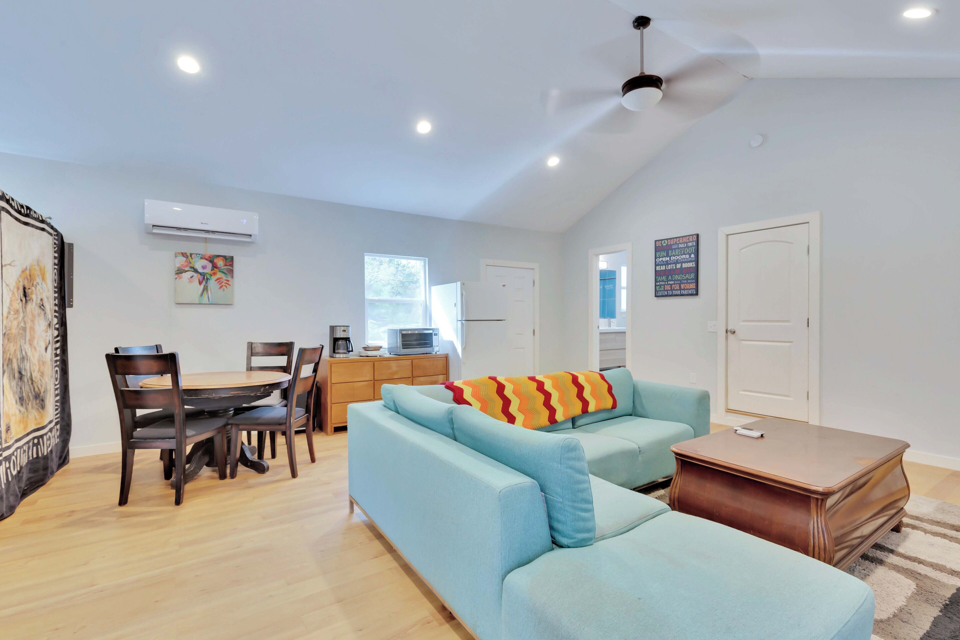 A modern living room with a sofa, dining table, chairs, and a coffee machine.