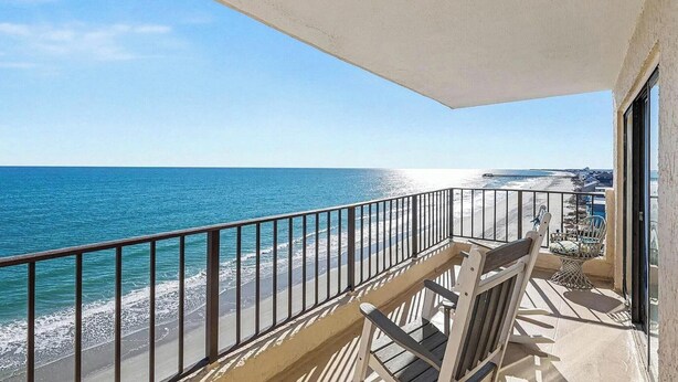 A balcony with a view of the ocean and beach, featuring a railing and a chair. - Oceanfront Oasis - Steps to Beach - Pool, Hot Tub & Elevator (Murrells Inlet)