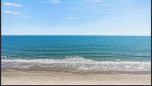A beach with clear blue water and a sandy shore. - Oceanfront Oasis - Steps to Beach - Pool, Hot Tub & Elevator (Murrells Inlet)