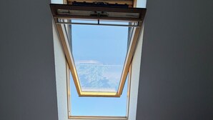 Una habitación con un tragaluz, una cama con colcha estampada de corazones y vista a un cuerpo de agua.