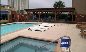 A swimming pool with lounge chairs and a covered area, surrounded by buildings. -  1-bedroom condo in South Padre Island with views of the beach, and Laguna Madre (South Padre Island)