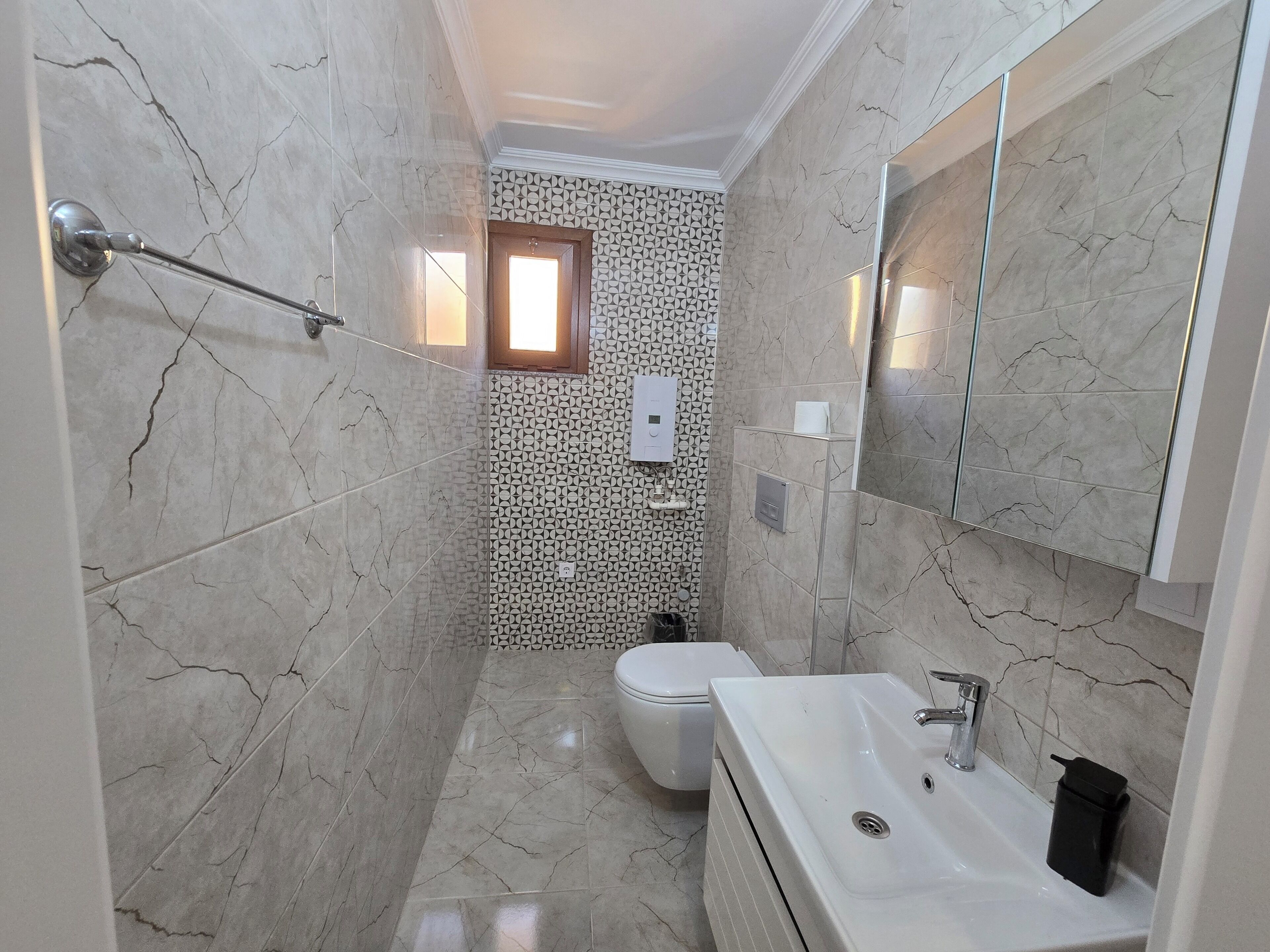 A bathroom with a shower, toilet, sink, and a mirror.