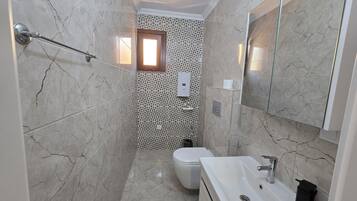 A bathroom with a shower, toilet, sink, and a mirror.