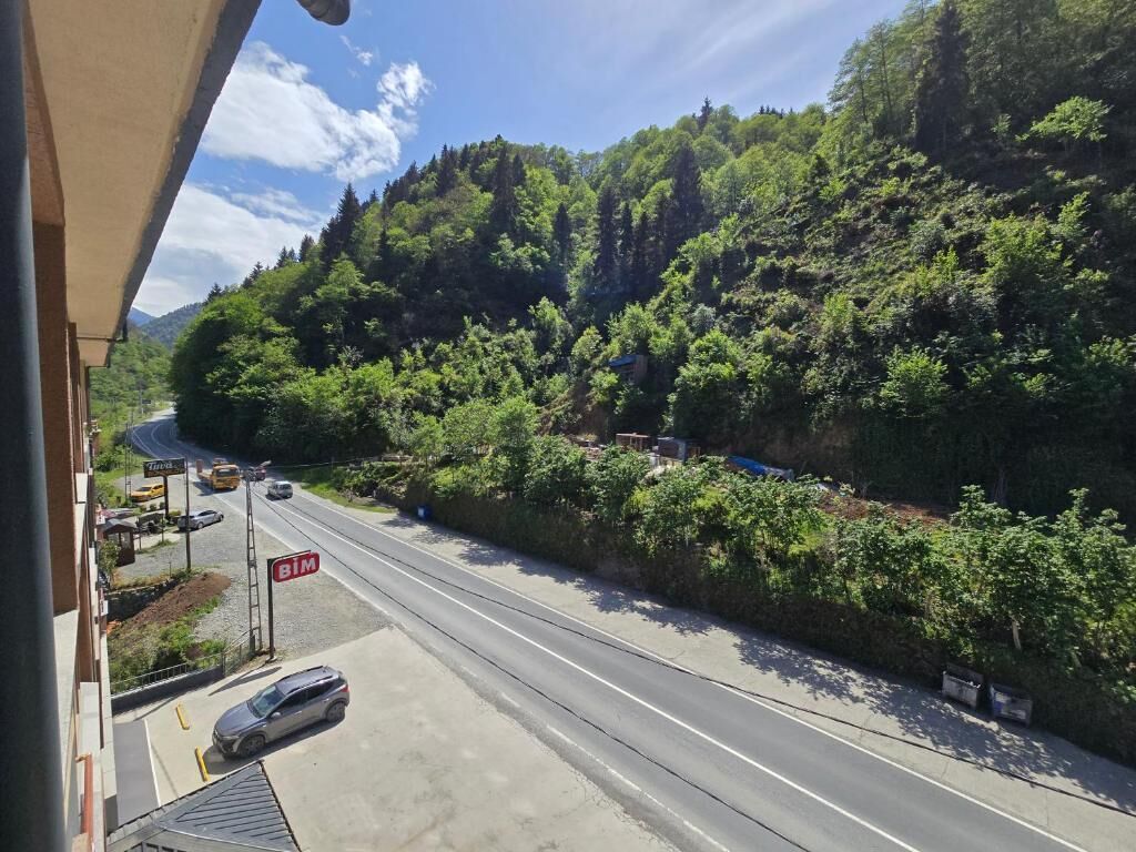 Une route avec un panneau indiquant « BIM », une voiture et un bâtiment doté d’un toit en pente.
