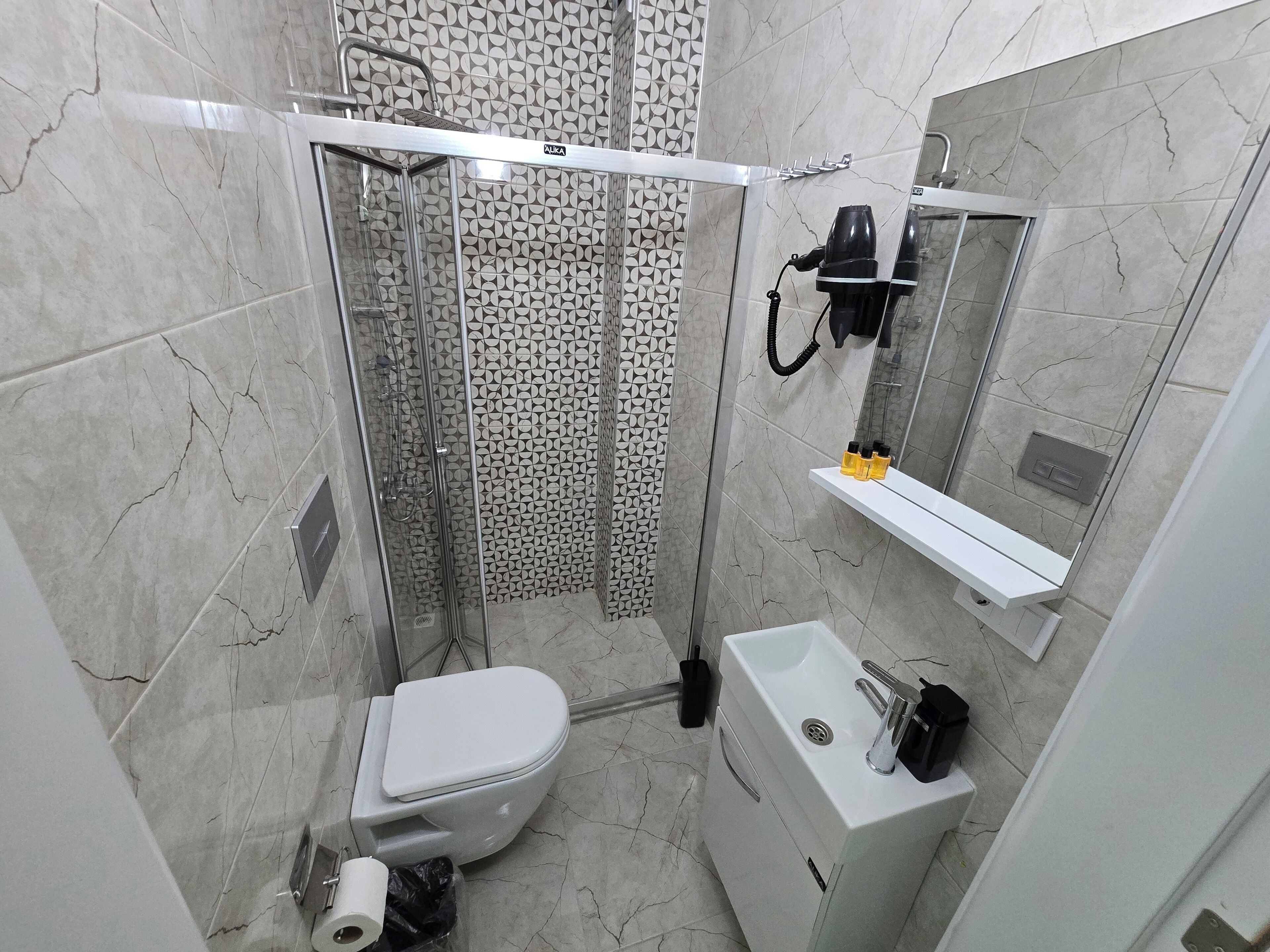 Un baño con inodoro, lavamanos, espejo y cabina de ducha.