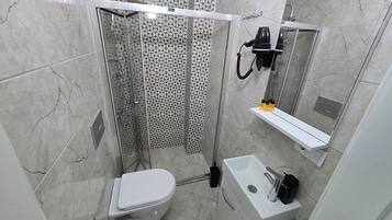 Un baño con inodoro, lavamanos, espejo y cabina de ducha.