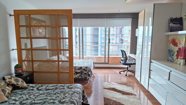 Een moderne slaapkamer met twee bedden, een bureau en uitzicht op de stad.