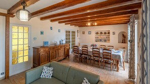 Uma sala de jantar com vigas de madeira, um lustre e uma mesa posta para quatro pessoas.