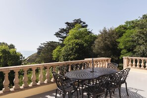A round metal table with chairs on a balcony with a balustrade, overlooking a mountainous landscape. - La chevreuse - Vue mer à moins de 300m de la plage (Lamballe)