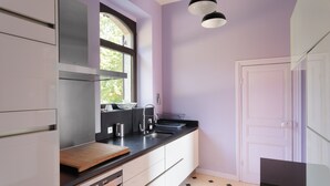 A modern kitchen with a large window, a black countertop, and a white door. - La chevreuse - Vue mer à moins de 300m de la plage (Lamballe)