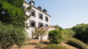 A large, two-story building with a prominent staircase, surrounded by dense greenery. - La chevreuse - Vue mer à moins de 300m de la plage (Lamballe)