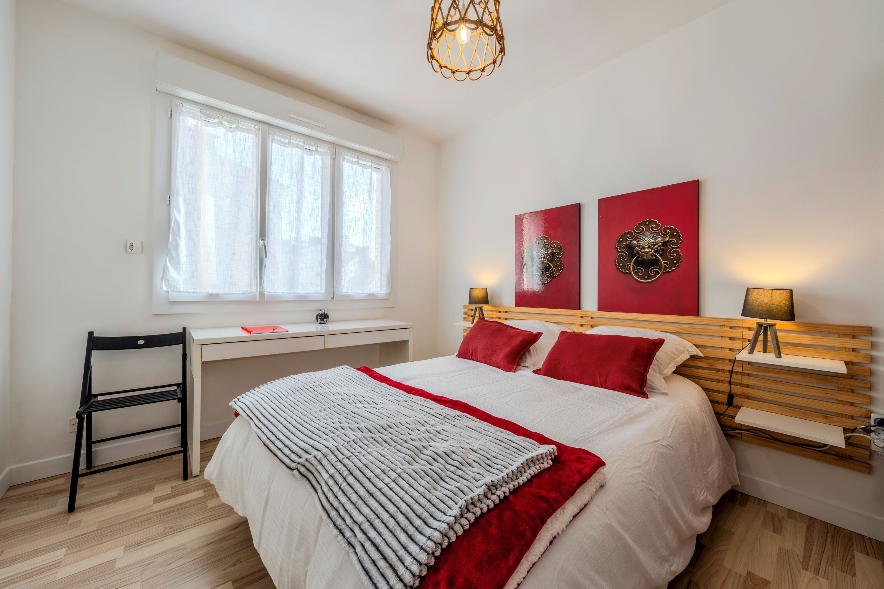 A bedroom with a bed, desk, chair, and artwork on the wall.