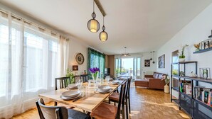 A dining area with a wooden table set for four, chairs, and hanging pendant lights. - La Terrasse de la Rade - Terrasse avec vue mer (Brest)