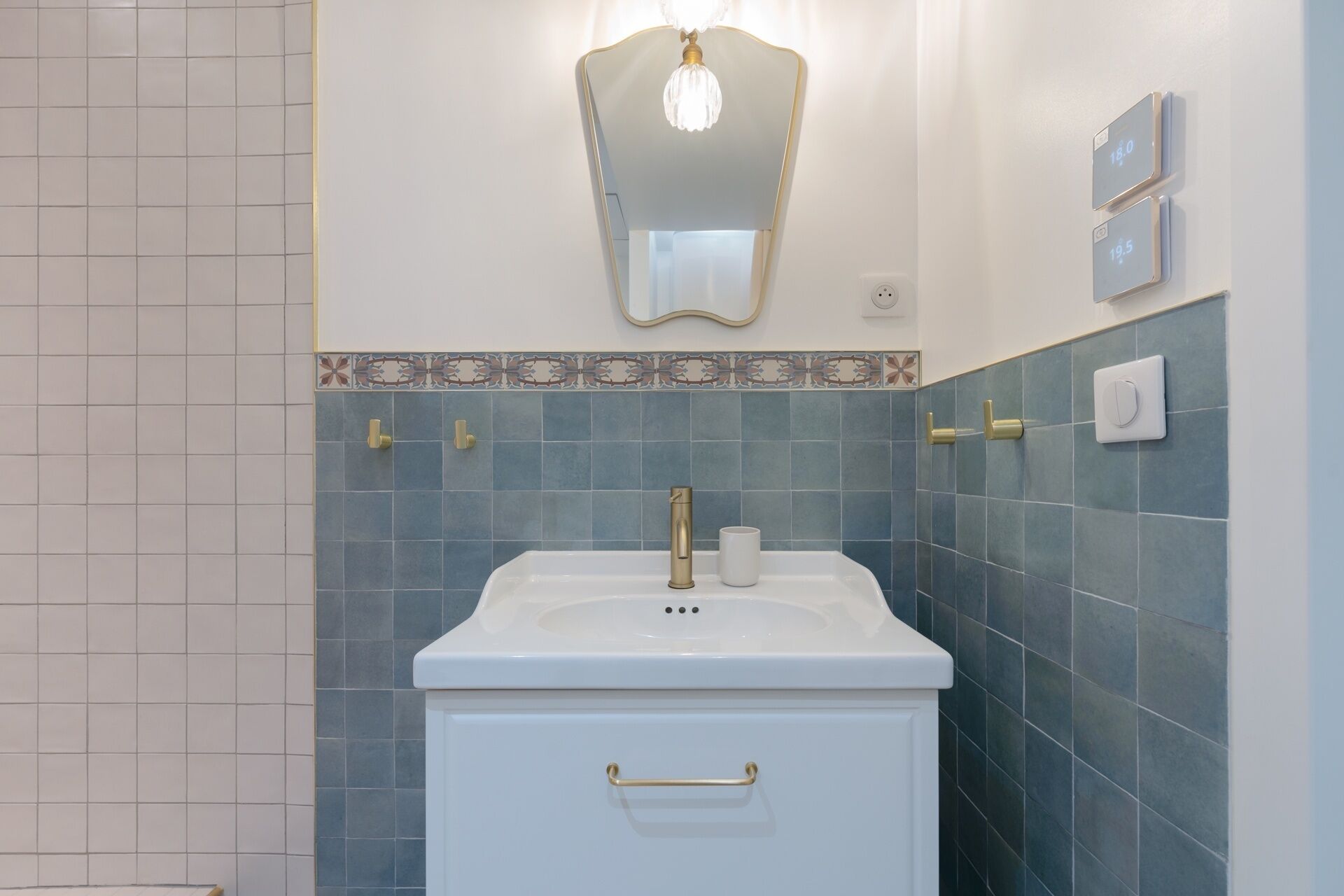 Un baño con un lavamanos blanco, grifo dorado y un espejo encima.
