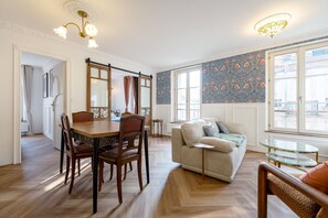 Ein Essbereich mit Holztisch und -stühlen, einer Couch, einem Glastisch und Blick auf die Stadt durch große Fenster.