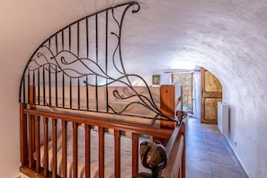 Un escalier en colimaçon avec une rampe en fer forgé, des marches en bois et un mur en pierre.