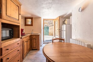 Une cuisine avec des meubles en bois, un four à micro-ondes, une bouilloire rouge et une table à manger.
