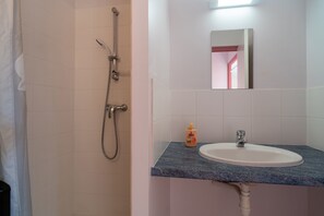Ein Badezimmer mit Dusche, Waschbecken und Spiegel.