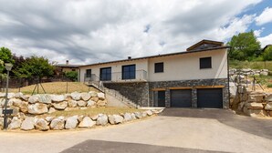 Ein modernes, zweistöckiges Haus mit Naturstein-Fassade, einer Haustreppe und einer Garage.